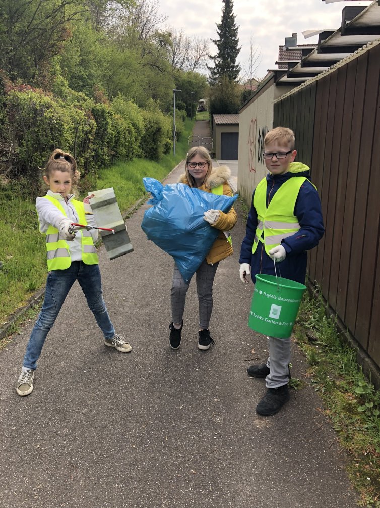 Drei Schüler - zwei Mädchen, ein Junge - bei einer Müllsammel Aktion